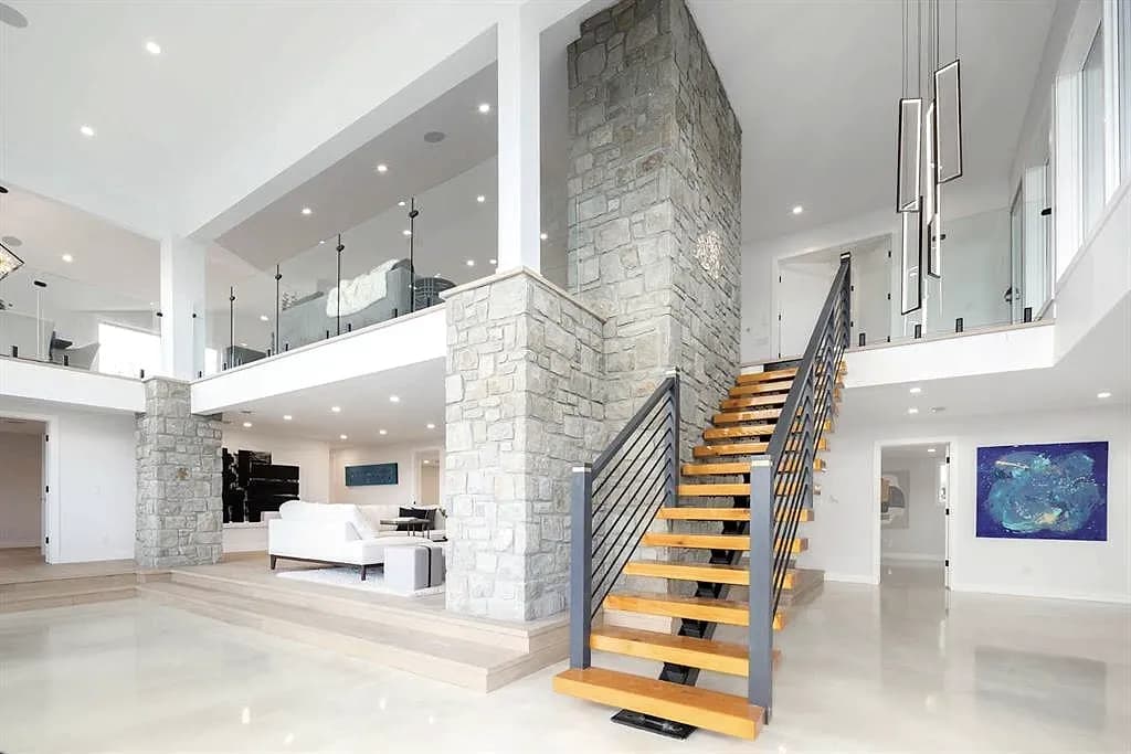 Open staircase with a horizontal metal railing beside a stone column