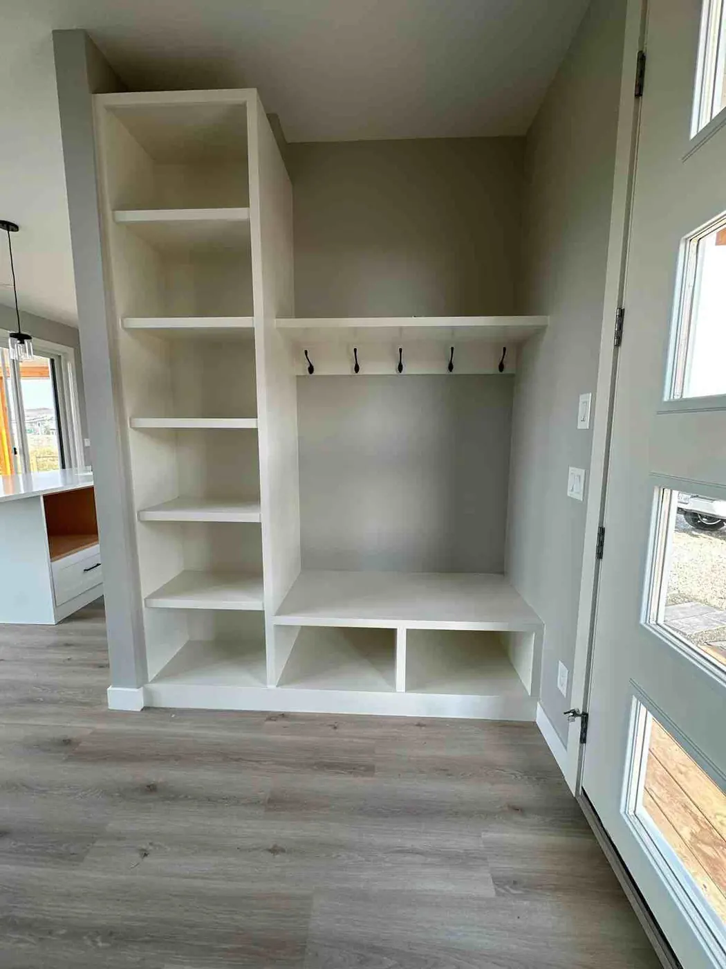 Mudroom built-in with a bench, cubbies, coat hooks and a tall open shelf unit