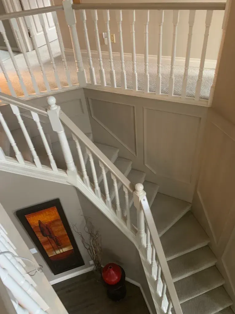 Before: the original white wood spindle railing on a staircase with panelled walls