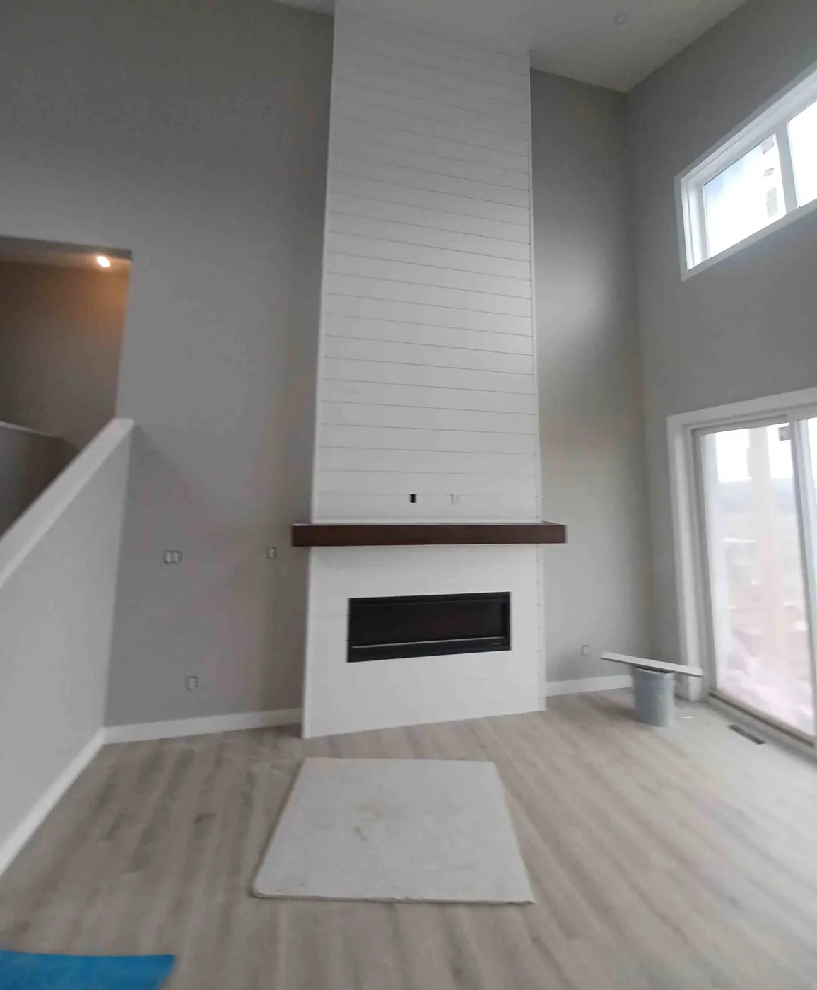 Shiplap fireplace surround with a dark wood mantel in a room with a vaulted ceiling