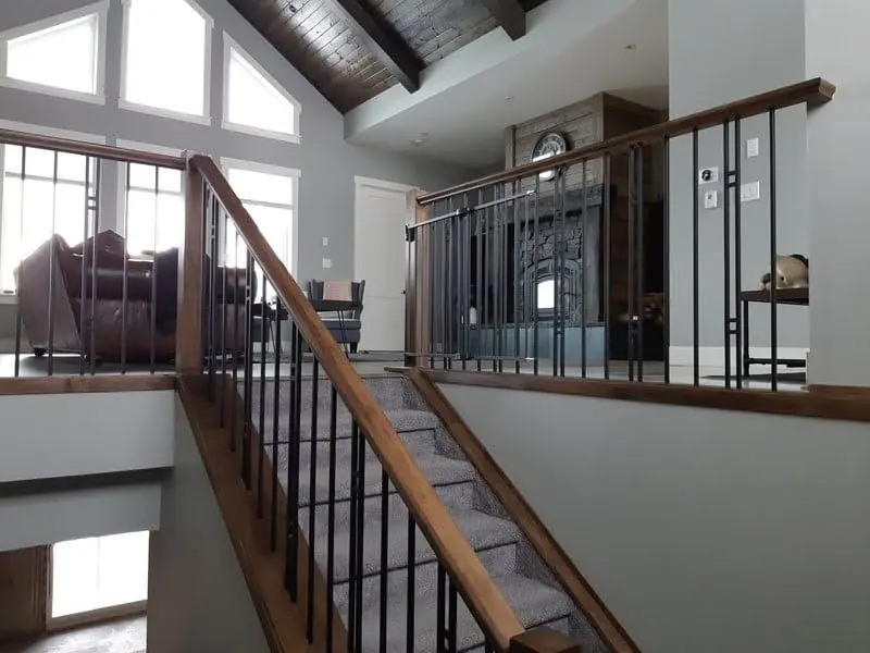 Stained handrail and black spindles on a staircase open to the living room