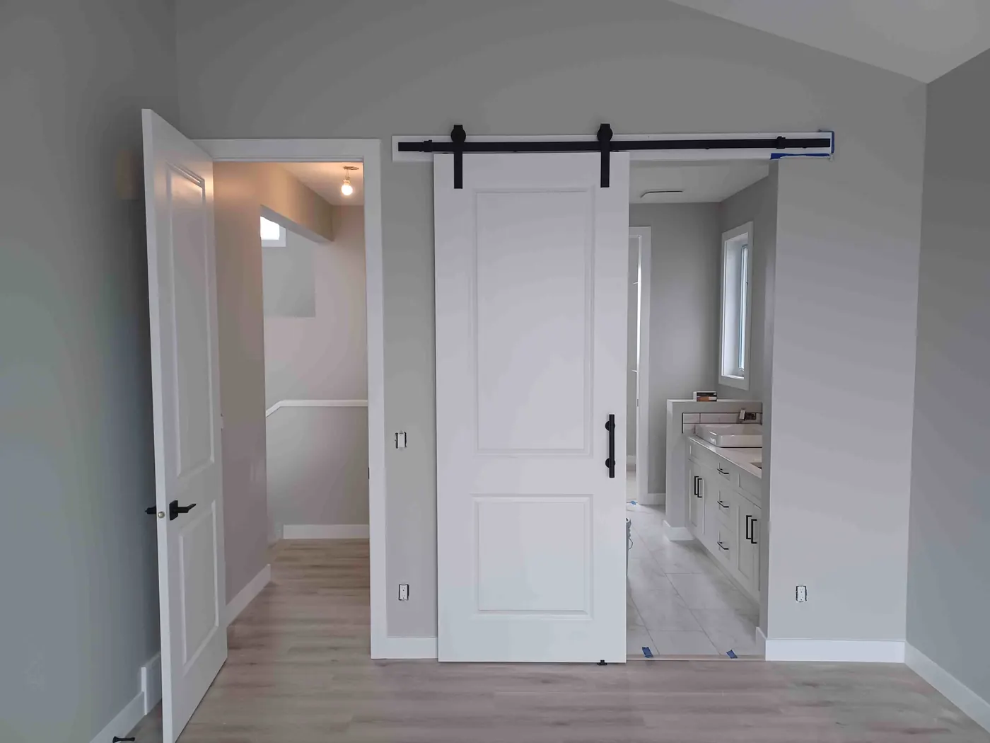 White panelled sliding barn door beside a hinged interior door