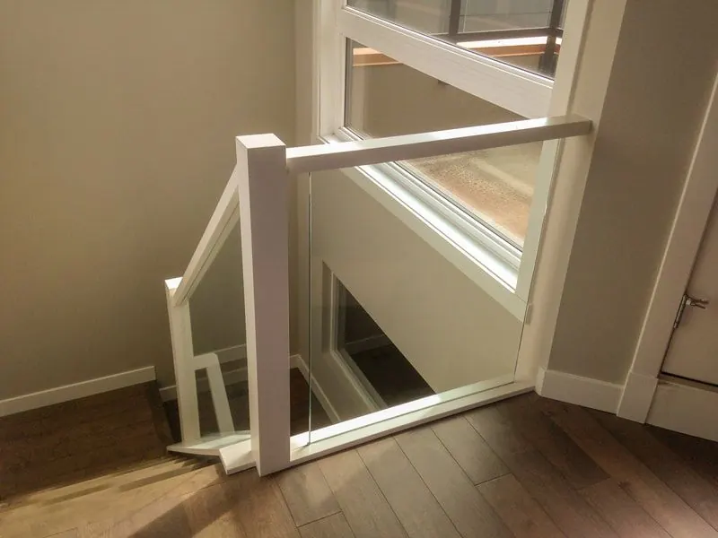Painted white wood railing with glass panels at a stair landing