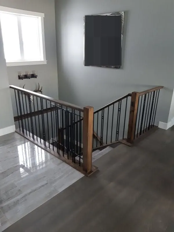 Wood handrail with black metal spindles around an open stairwell