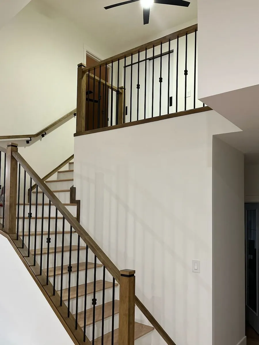 Stained wood stair railing with black metal spindles