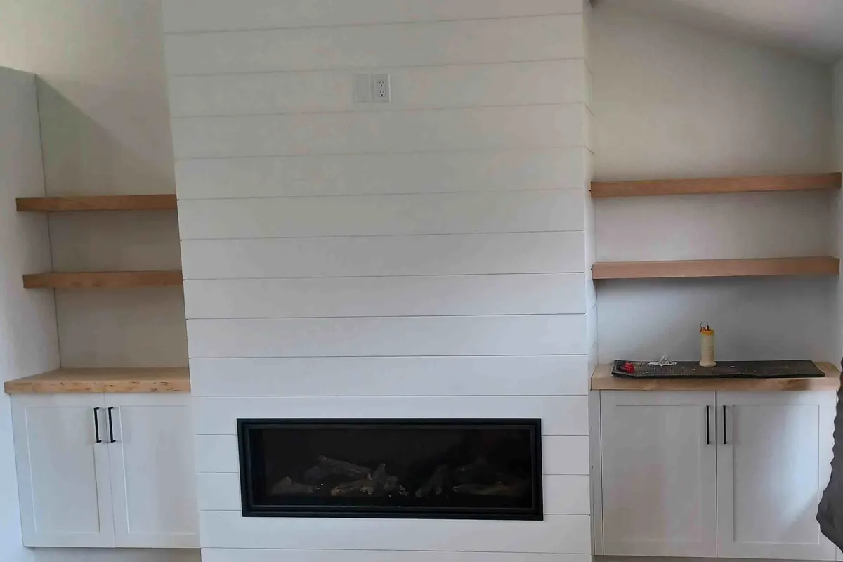 Fireplace wall with built-in cabinets and wood floating shelves on each side